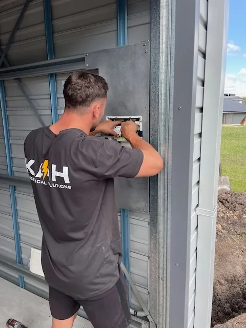 Electrician working on a panel in a metal building.
