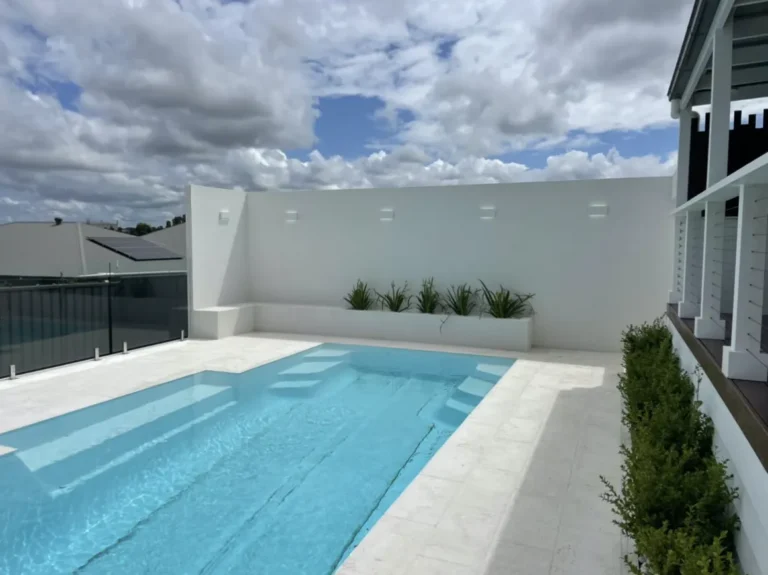 Modern rooftop pool with white surroundings.