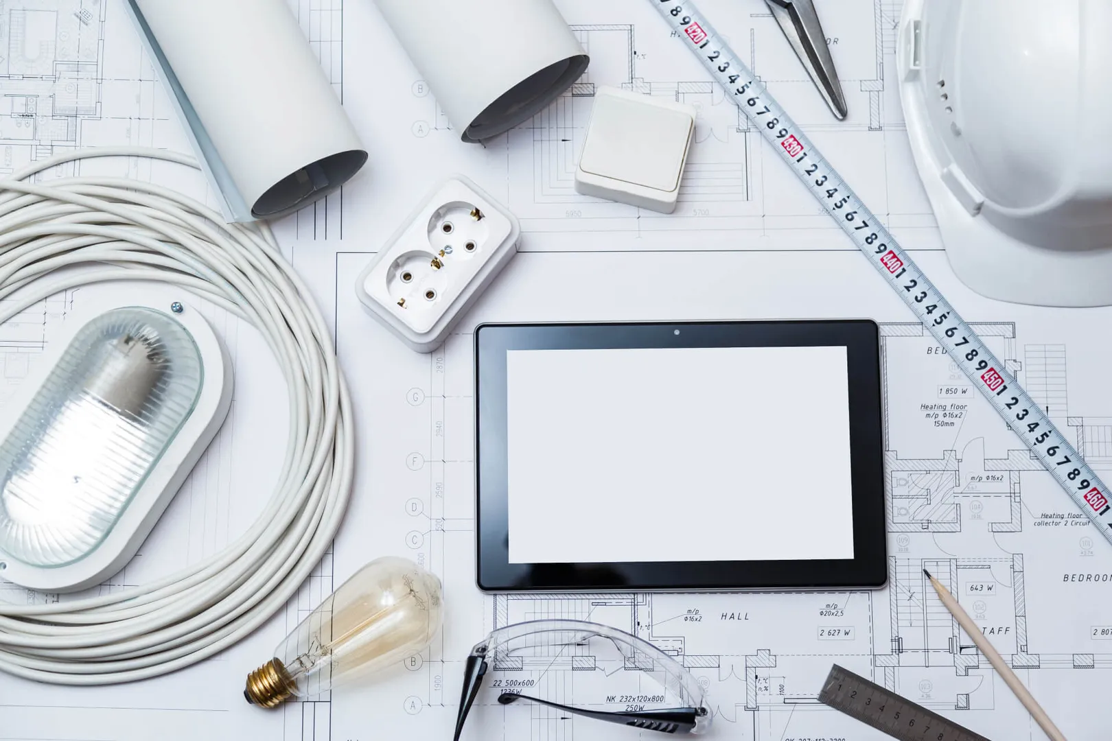 Electrical tools on blueprints, hard hat, and tablet