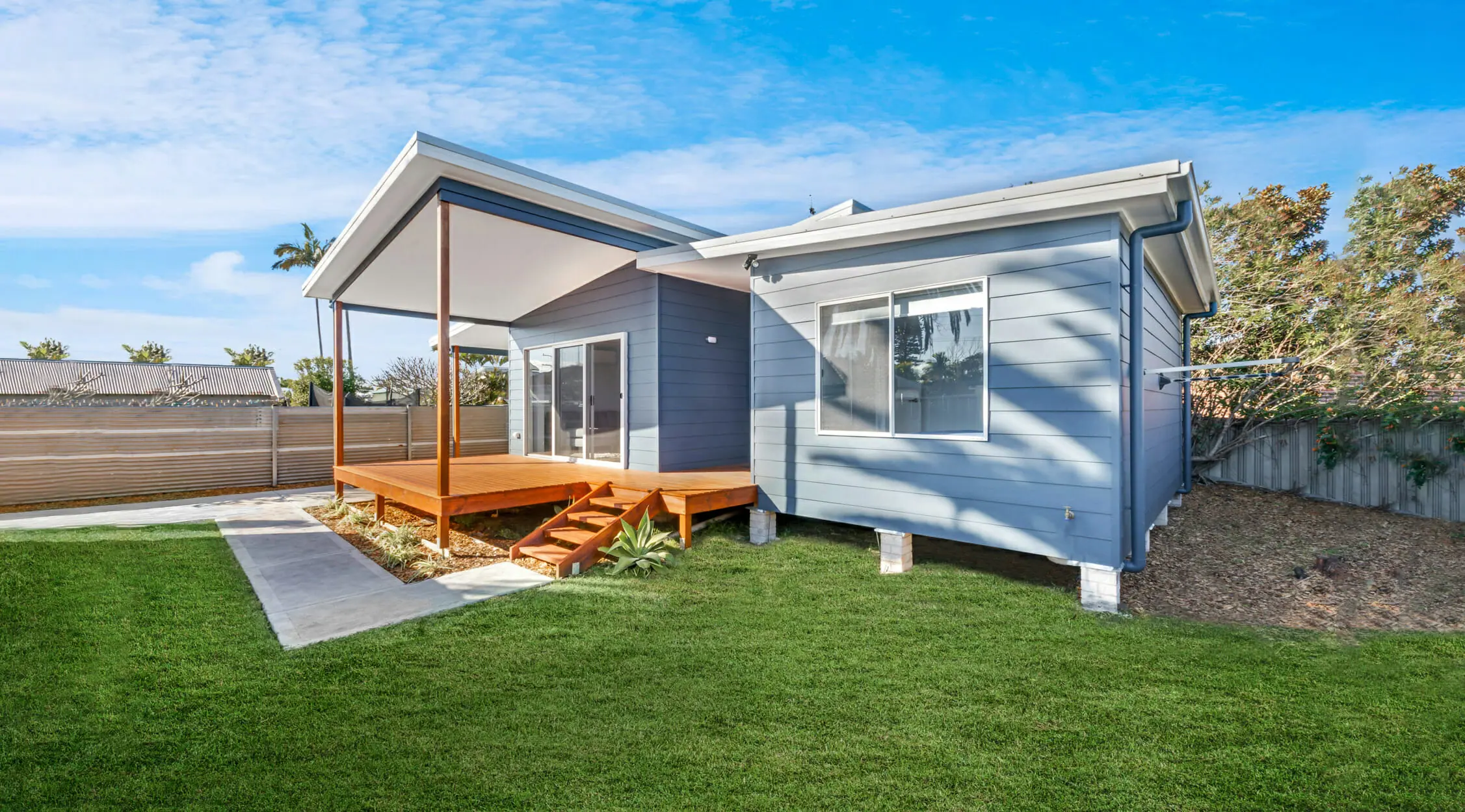 Modern house with wooden deck and green lawn